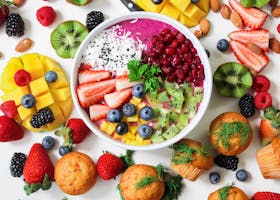 Vibrant smoothie bowl topped with assorted fresh fruits and muffins, perfect for a healthy snack.