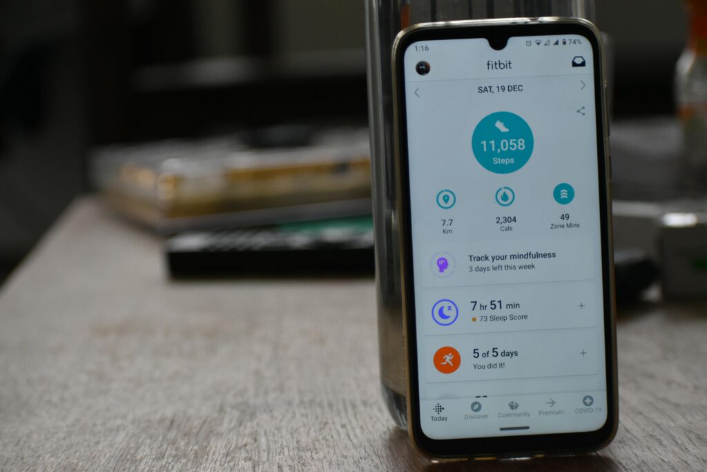 Close-up of a smartphone displaying a fitness tracking app with health statistics, alongside a smartwatch.