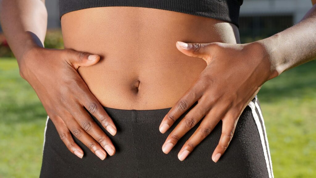 Close-up of a person placing hands on their stomach outdoors, emphasising digestion and wellbeing.